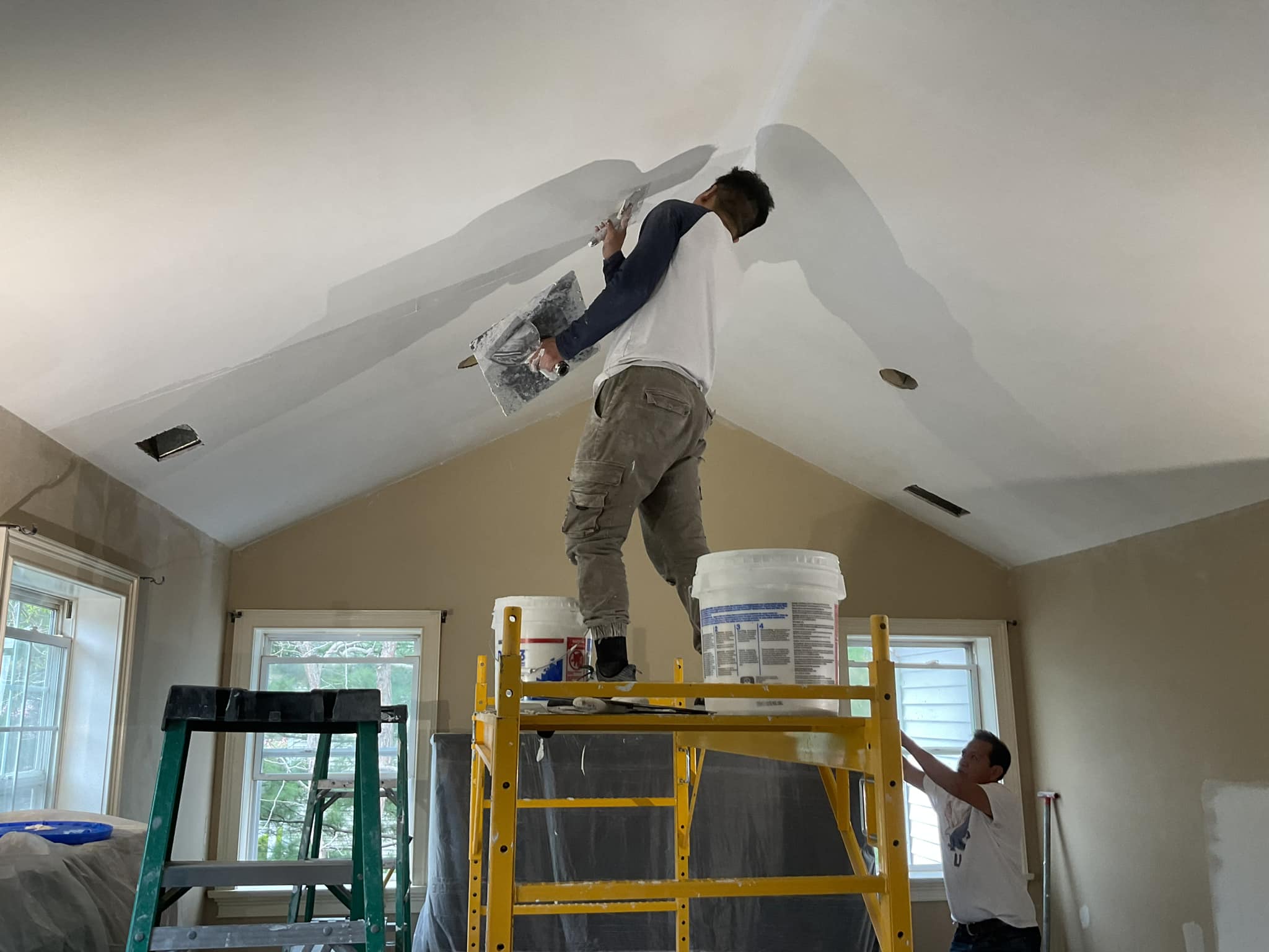 Technicians apply caulking to ceiling